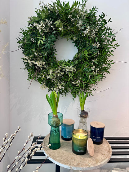 Vista lateral de corona natural con follaje verde y flores blancas